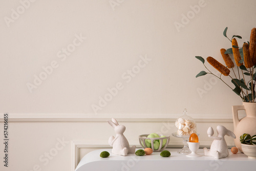 Sticker Creative composition of easter living room interior with copy space, beige vase with dried flowers, glass easter eggs, easter bunny sculpture and personal accessories