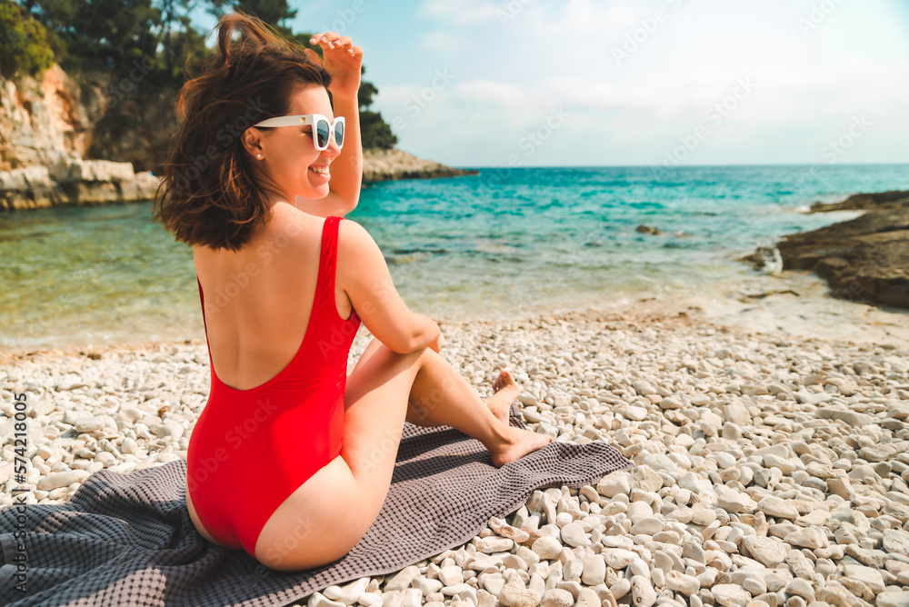 woman sitting on blanket at sea beach