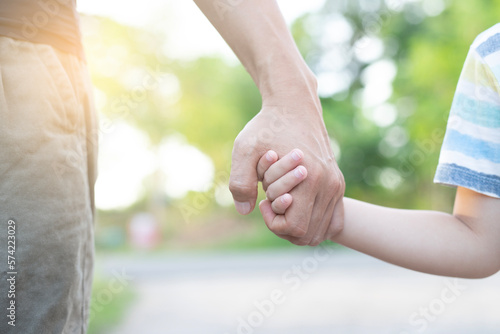 Father's hand leads his son in the park summer outdoor nature family trust concept