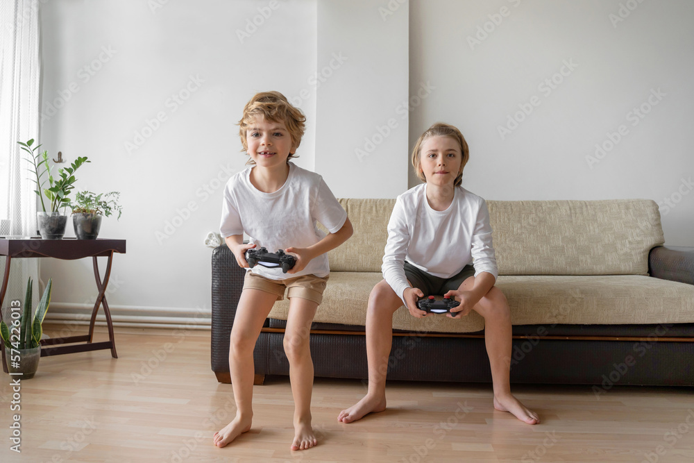 Funny caucasian siblings passionately playing video games in front of tv, two brother sister expressing emotions while enjoying their hobby playstation joystick. Copy space Funny caucasian siblings passionately playing video games in front of tv, two brother sister expressing emotions while enjoying their hobby playstation joystick. Copy space