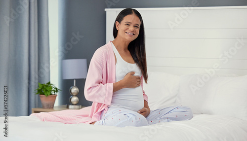 Pregnant woman, portrait and stomach in home bedroom happy about bonding and growth. Mother to be person with hands on abdomen for healthy pregnancy development, body wellness and love or care on bed