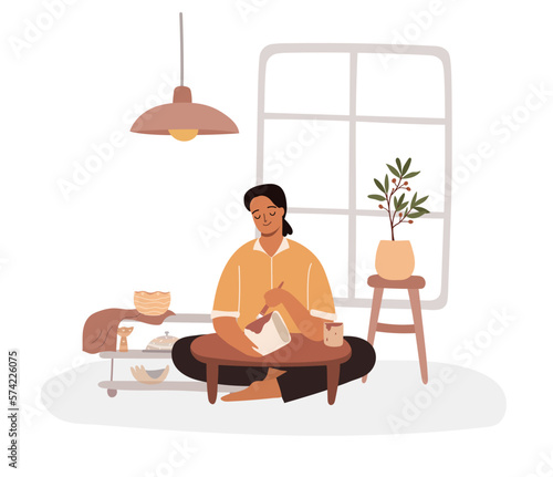 African woman working on pottery wheel in studio. Female ceramist painting a pot concept.