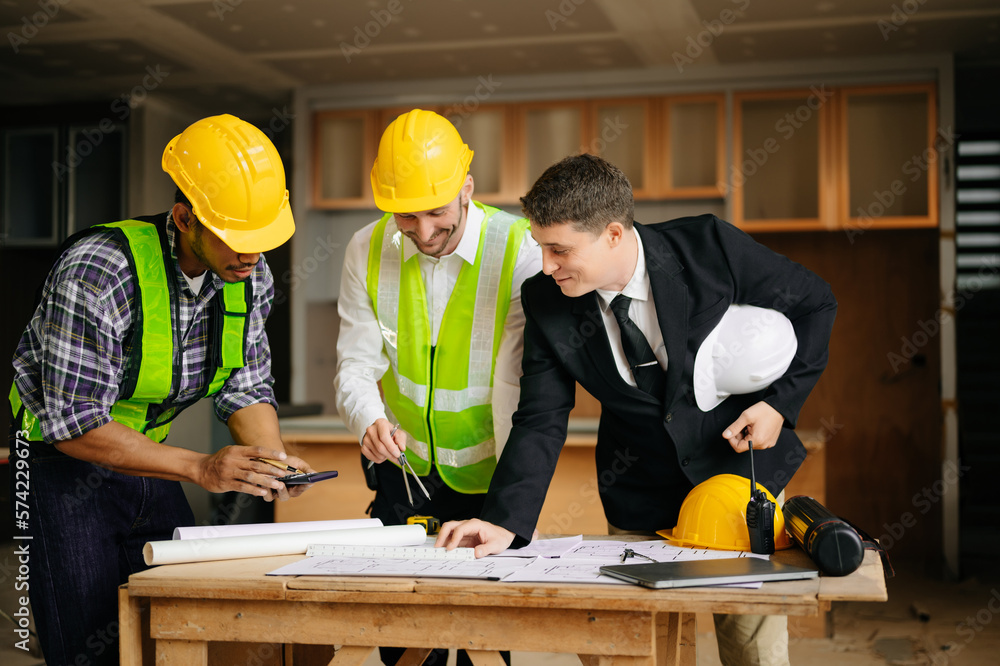 Engineers are discussing data working and laptop or tablet with architectural project at new construction site on big project. interior.