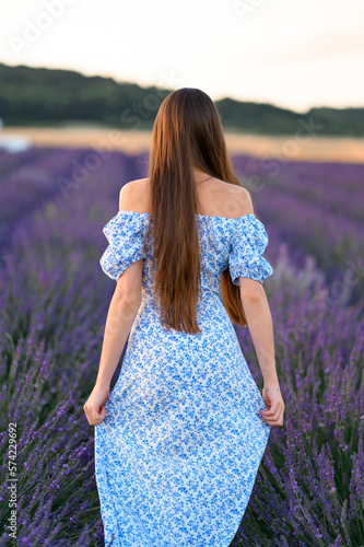 Fototapeta Naklejka Na Ścianę i Meble -  Attractive slender happy girl in a blue dress in a lavender field at sunset.