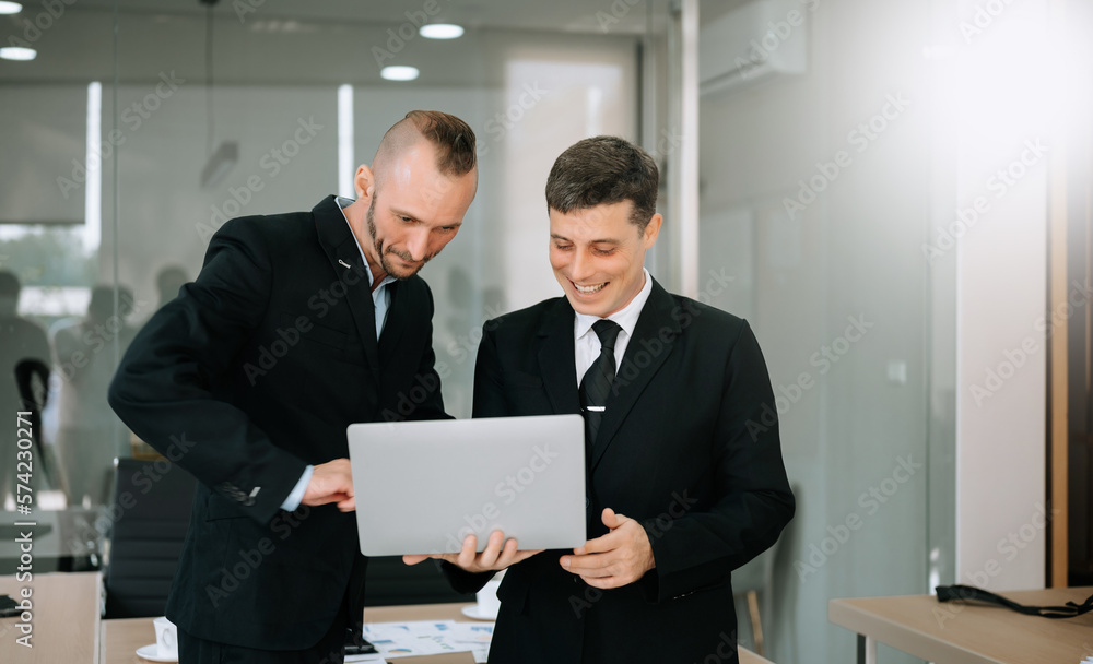 Male discussing new project with male colleague. Mature man talking with young man in office. Male discussing new project with male colleague. Mature man talking with young man in office.