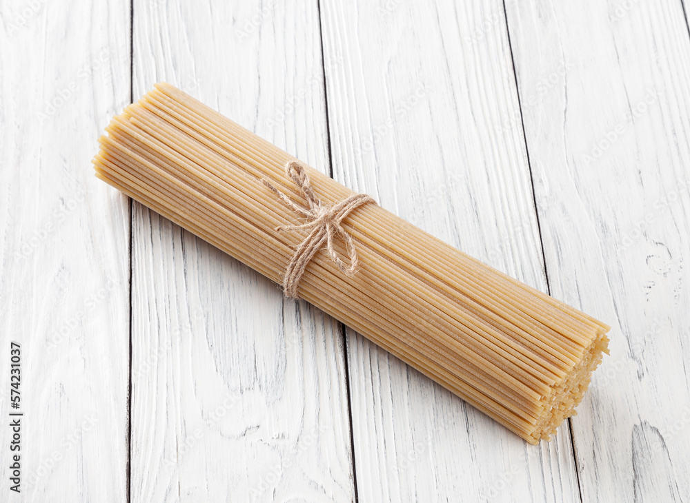 Uncooked spaghetti pasta on white wooden background