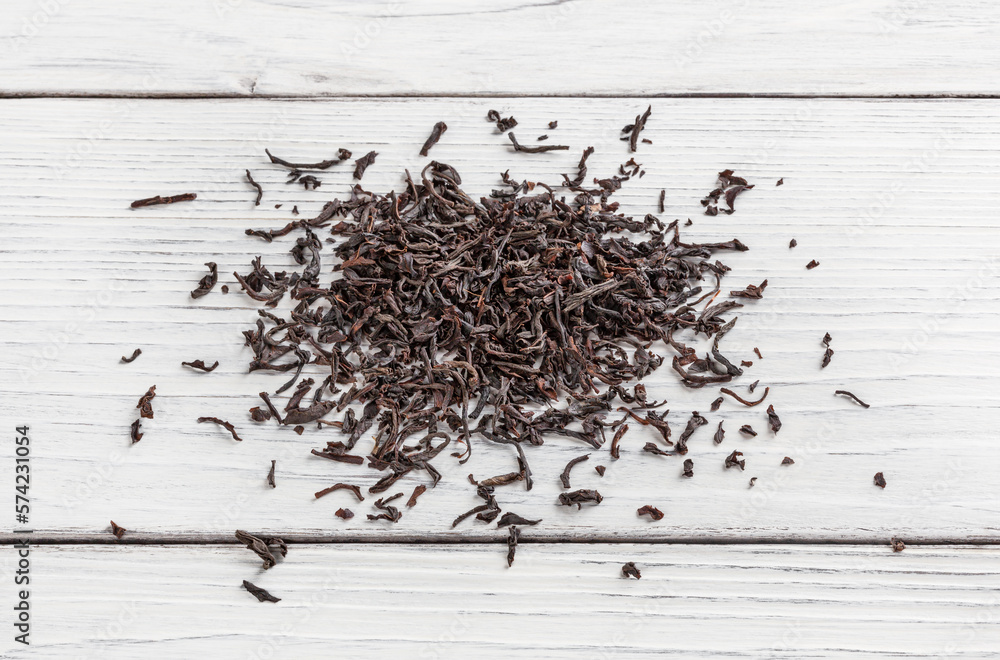 Heap of black tea on white wooden table