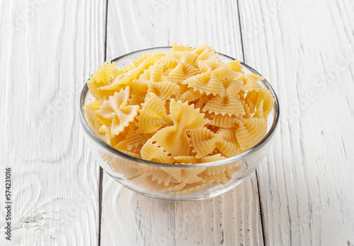 Obraz na płótnie Uncooked farfalle rigate pasta on white wooden background w salonie