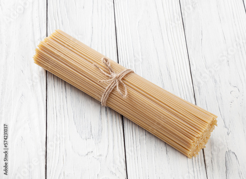 Obraz na płótnie Uncooked spaghetti pasta on white wooden background w salonie