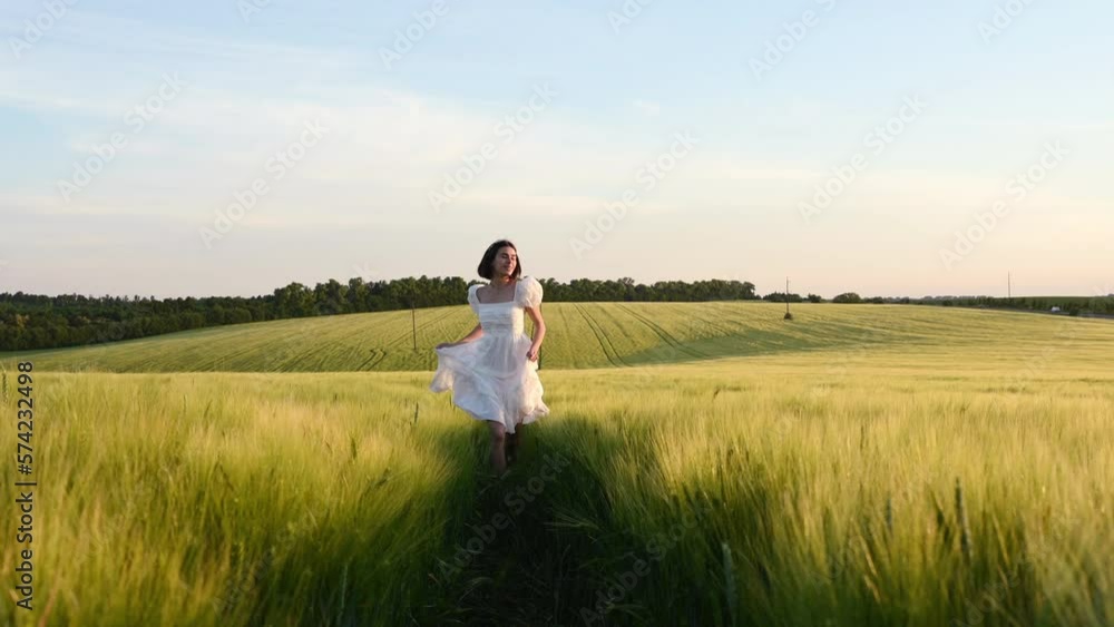 Happy young woman in white dress running on the field with wheat. Majestic landscape. Happy young woman in white dress running on the field with wheat. Majestic landscape.