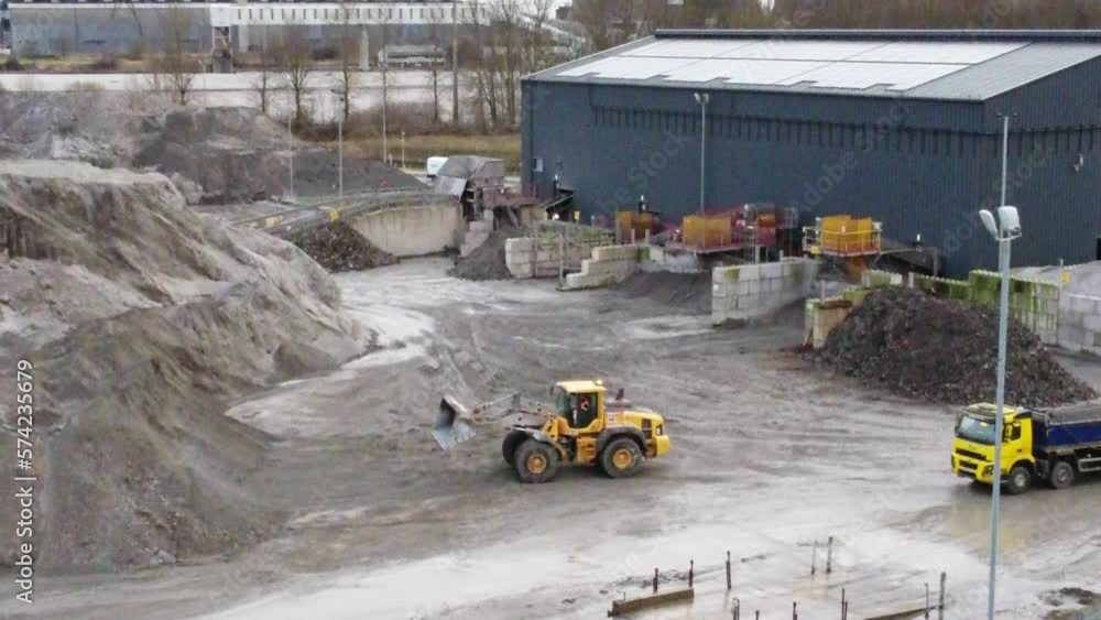 Aerial view, Bulldozer preparing to dump material into loader truck on UK power station coal resource site, tilting up Aerial view, Bulldozer preparing to dump material into loader truck on UK power station coal resource site, tilting up