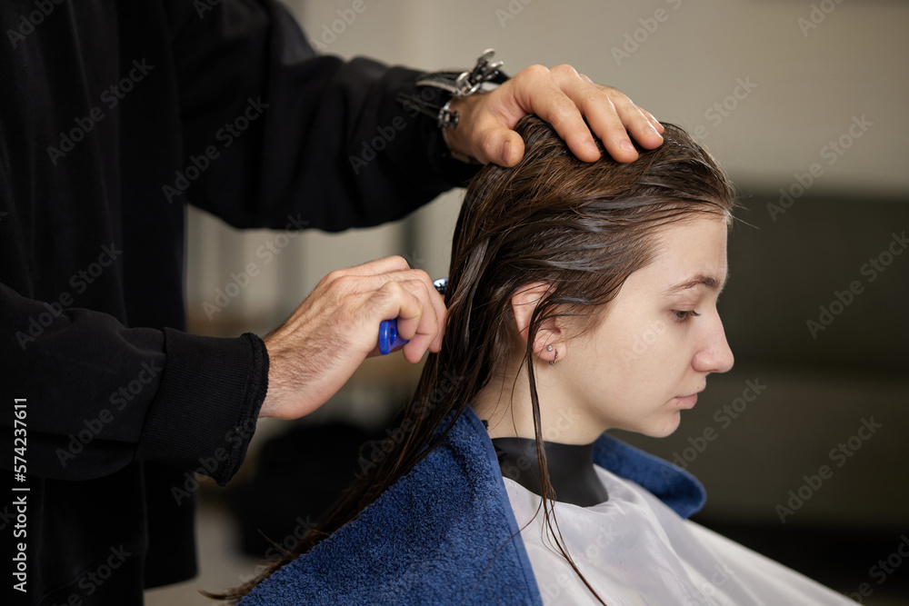 Fototapeta premium male hairdresser is combing the hair of the female client.