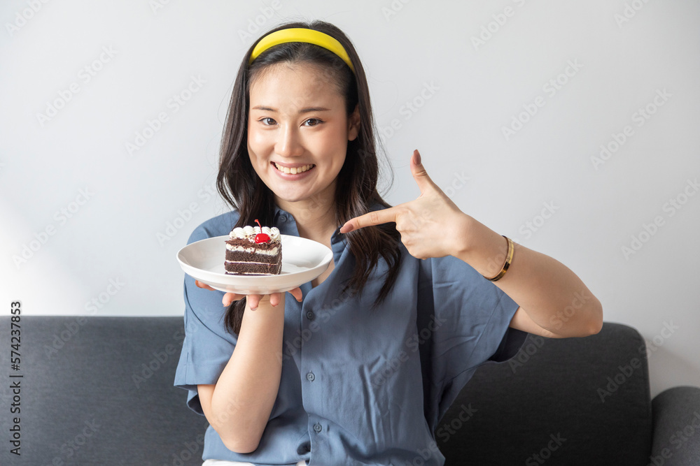 Young Chinese woman eating blueberry cake smiling happy and positive, thumb up doing excellent and approval sign. Young Chinese woman eating blueberry cake smiling happy and positive, thumb up doing excellent and approval sign.