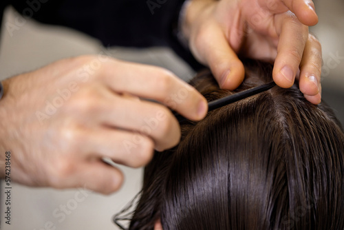 male hairdresser is combing the hair of the female client.