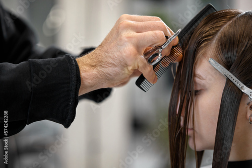 male hairdresser is combing the hair of the female client.