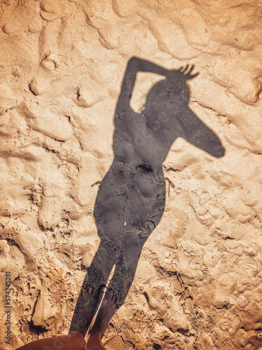 The shadow of the girl falls on the sand
