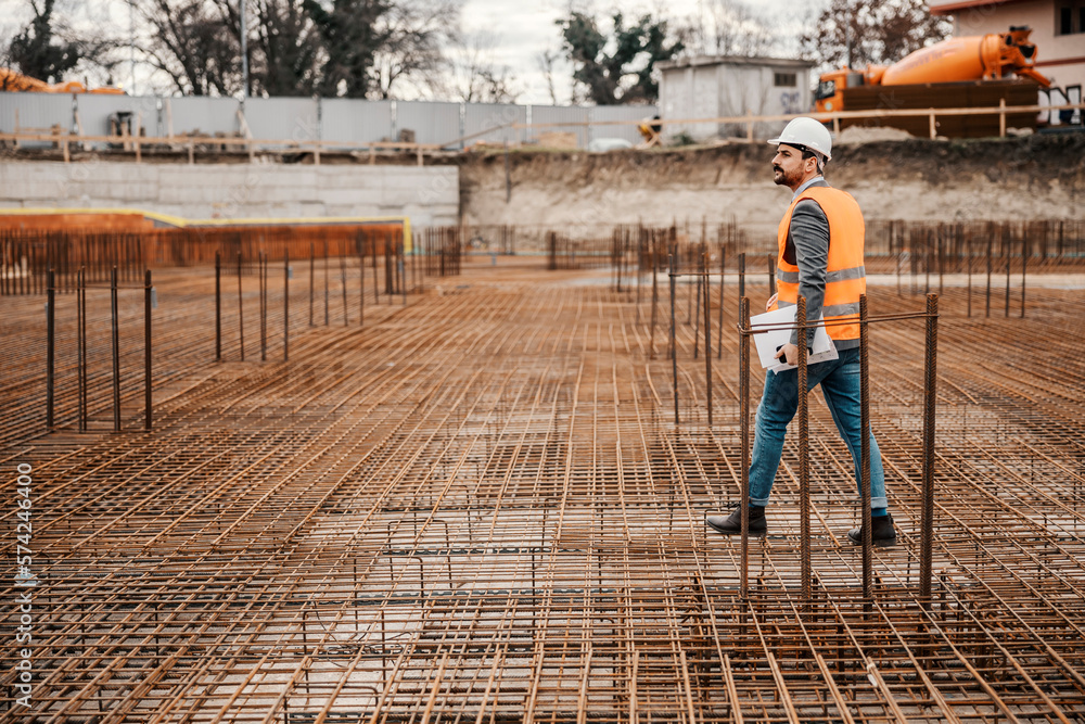 A construction site manager is walking around site and visiting works.