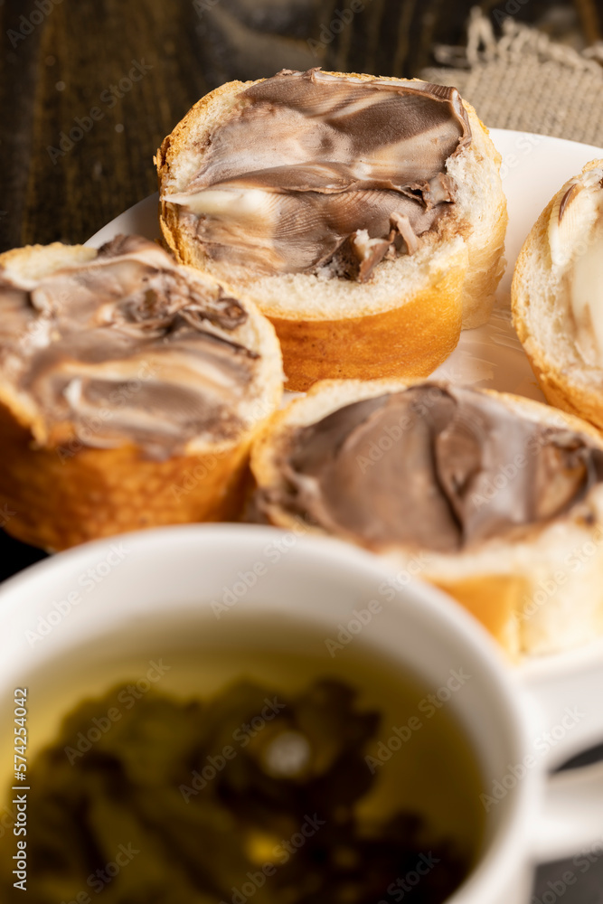 Green tea brewed in a mug and a baguette with chocolate butter Green tea brewed in a mug and a baguette with chocolate butter