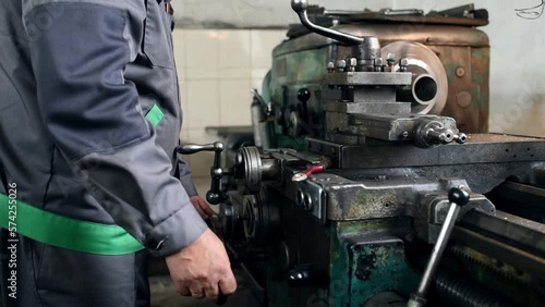 Man in uniform is operating cutting machine in the factory.