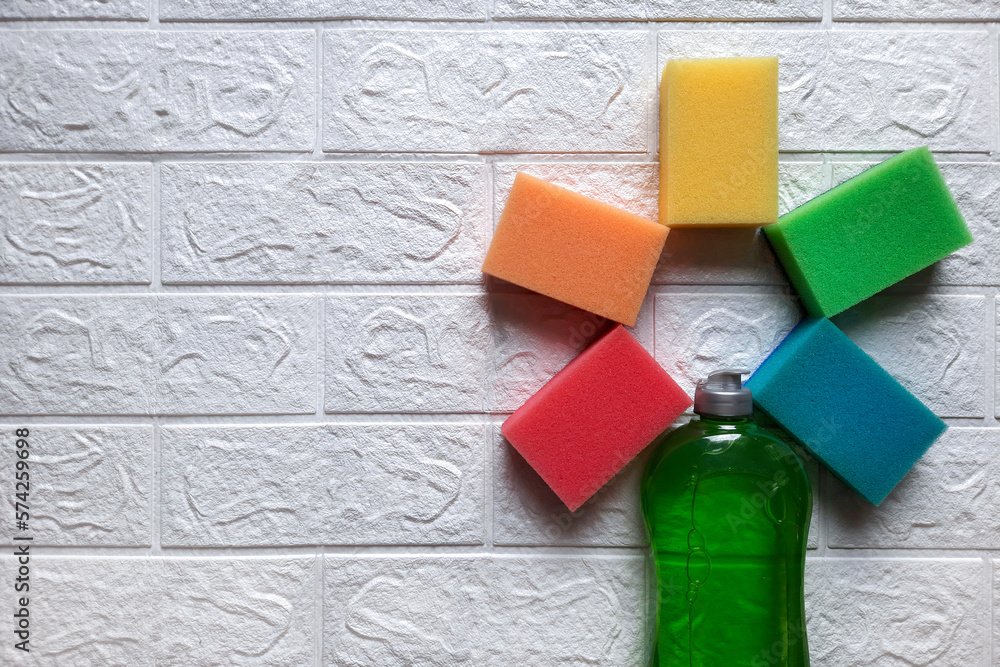 Kitchen sponges and dish detergent in form of flower. Flatlay. Space for text. Set of cleaning products in an unusual combination on white brick wall background. Concept of creative approach to advert Kitchen sponges and dish detergent in form of flower. Flatlay. Space for text. Set of cleaning products in an unusual combination on white brick wall background. Concept of creative approach to advert