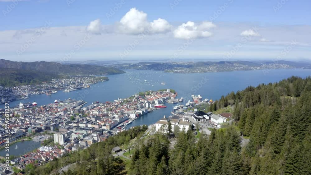 Beautiful drone shot flying over the restaurant and viewpoint on Mount Fløyen, revealing the gorgeous city of Bergen beneath the mountain. Beautiful drone shot flying over the restaurant and viewpoint on Mount Fløyen, revealing the gorgeous city of Bergen beneath the mountain.