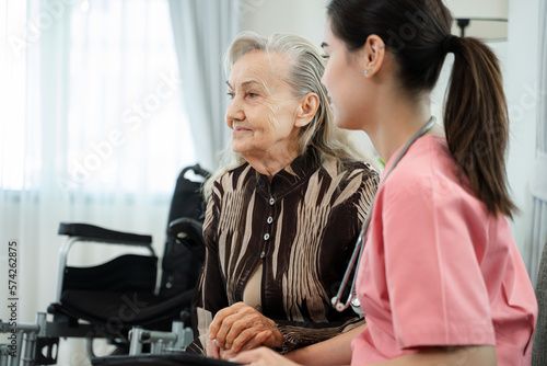 Nurse sitting beside senior woman and holding hands to encourage to cure,Medical care for the senior at home concept.