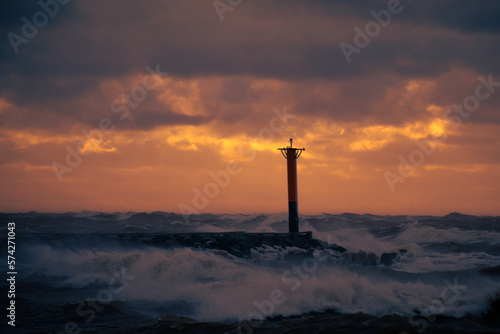 lighthouse on a windy storm on a baltic sea at winter with clouds in the sky