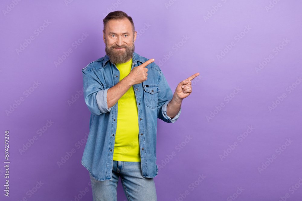 Portrait of positive aged person indicate fingers empty space proposition isolated on purple color background Portrait of positive aged person indicate fingers empty space proposition isolated on purple color background