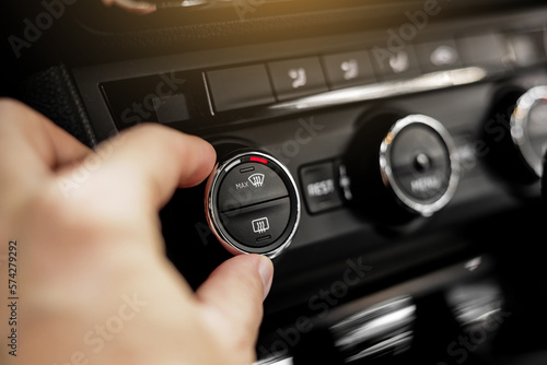 Closeup of hand adjusting the conditioner in a modern car. Dashboard with air flow, climate control and temperature button temperature button inside transport. Car HVAC System. Detail interior of car photo