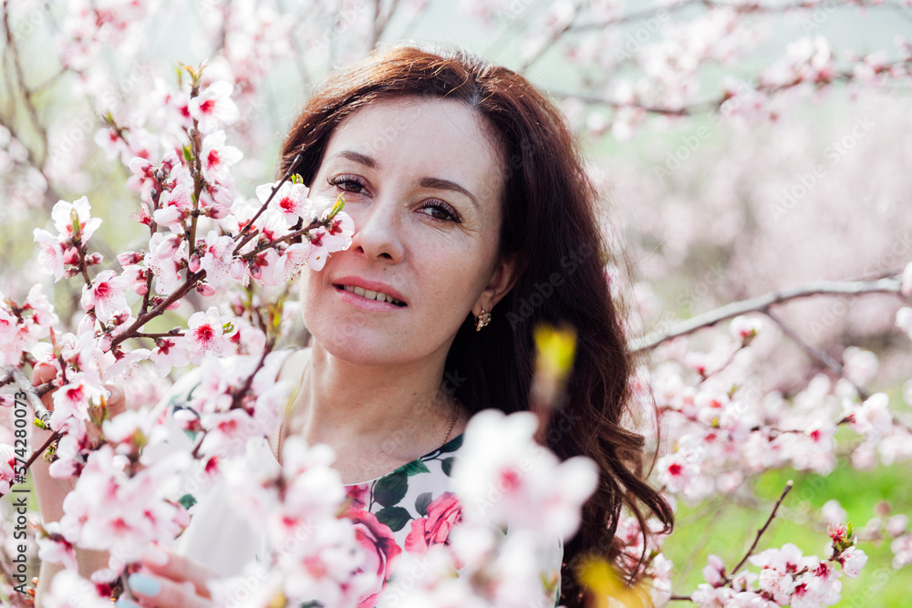portrait of a beautiful brunette woman in pink flowers on the street in a blooming garden portrait of a beautiful brunette woman in pink flowers on the street in a blooming garden