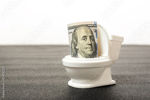 Dollar bill in toilet close up. Concept of waste of money, throwing money down the toilet. Devaluation and inflation of the dollar.