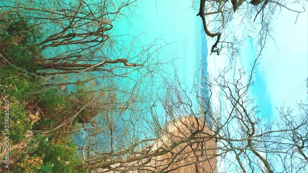 Panoramic view of the Black Sea coast from the mountain through the branches of trees. View of the blue water and the rocky seashore from the Kiselyov cliff. Sunset on the beach. 4K Panoramic view of the Black Sea coast from the mountain through the branches of trees. View of the blue water and the rocky seashore from the Kiselyov cliff. Sunset on the beach. 4K