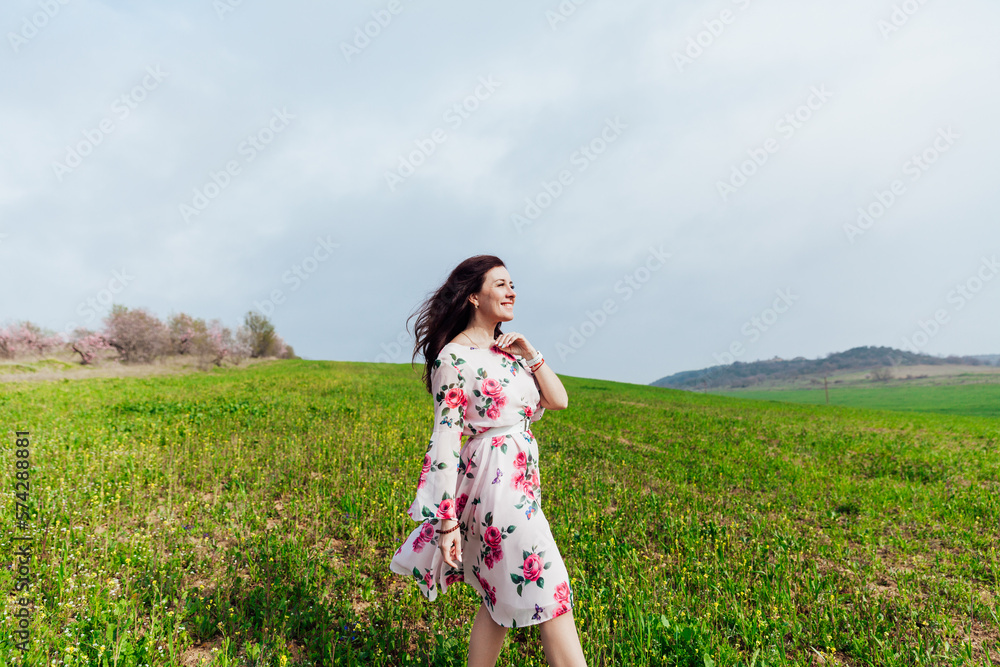 a cheerful woman stands in a green field in nature