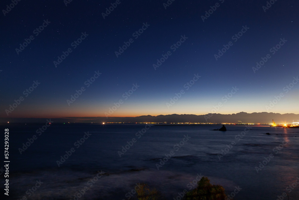 Fototapeta premium 夜明けの空に残る星々と白波の富山湾