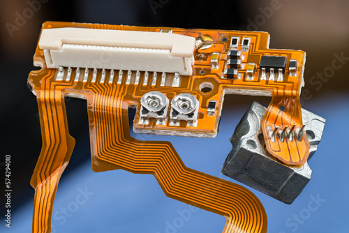 Photography Orange printed circuit board with flex ribbon cables, small electronic components and white connector