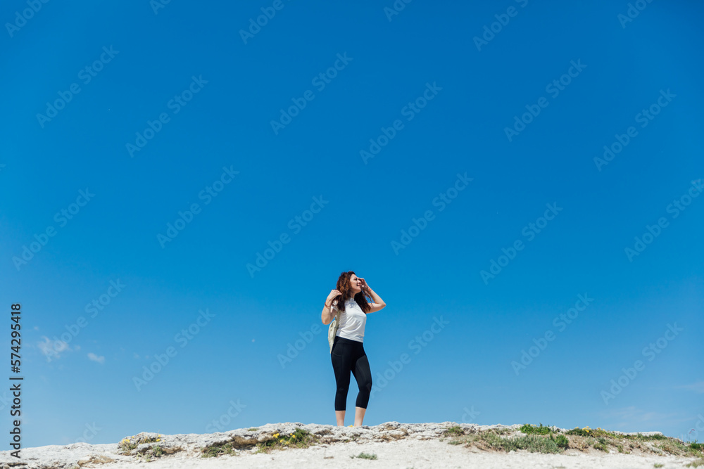 Obraz premium a woman standing on a mountain under a blue sky hiking journey