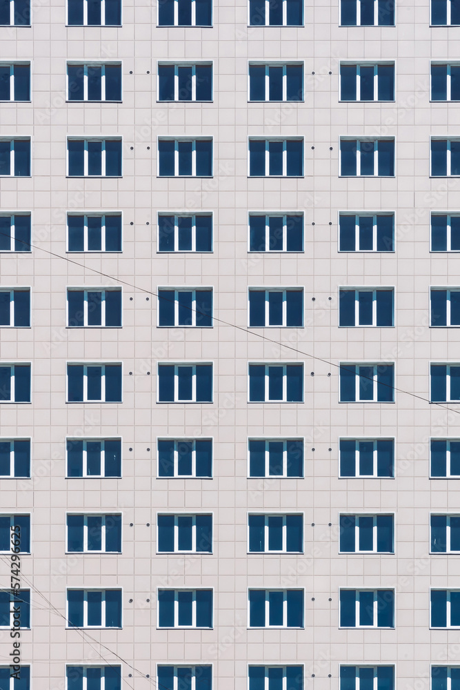 Geometric backdrop with lots of window rows. Simple classic design high-rise building. Realistic concept of office building. Apartment house texture background. Many windows on big wall close-up. Geometric backdrop with lots of window rows. Simple classic design high-rise building. Realistic concept of office building. Apartment house texture background. Many windows on big wall close-up.