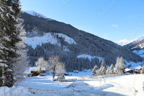 an ice covered rural road and some farm houses in a mountain valley on a beautiful cold winter morning with fresh snow