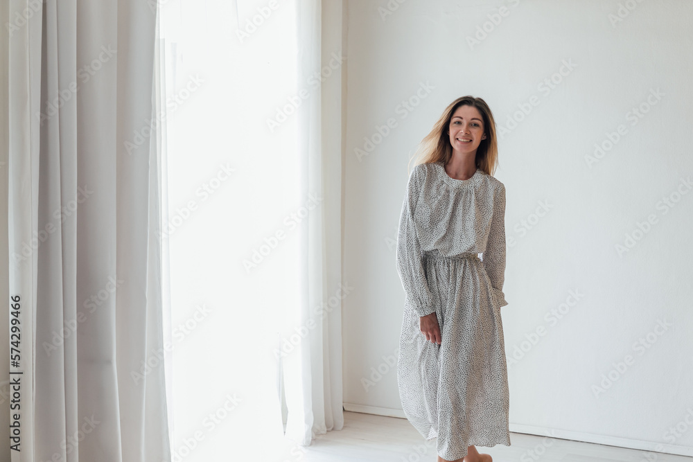 a blonde woman in a dress stands in a bright room a blonde woman in a dress stands in a bright room