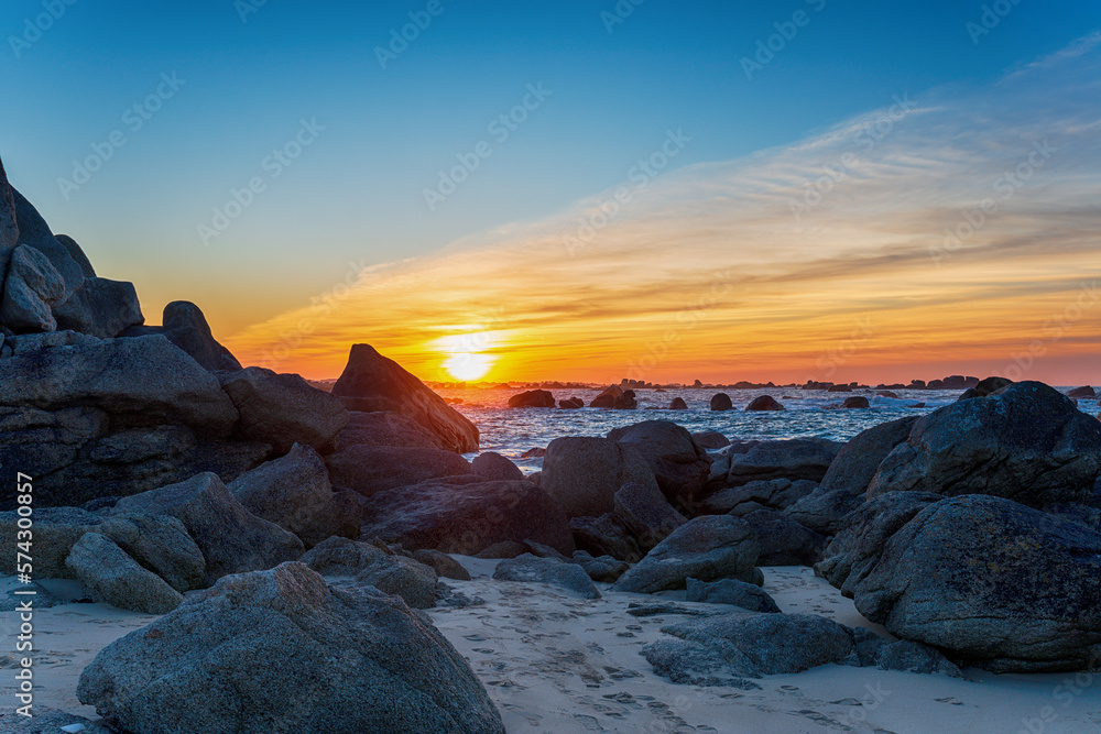 Sunset over rocks on the beach at Meneham
