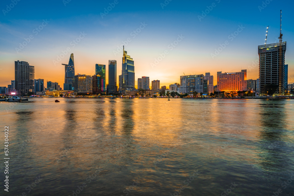 Fototapeta premium Beautiful Sunset at Bitexco in Ho Chi Minh City, the famous building in Vietnam, with Vietnam flag on the top building. Colorful sky background. Travel concept