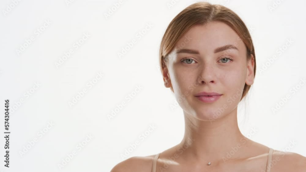 Attractive young slim brown-haired Caucasian woman strokes her jawline turning her head to the camera on white background | Anti-aging cosmetics commercial Attractive young slim brown-haired Caucasian woman strokes her jawline turning her head to the camera on white background | Anti-aging cosmetics commercial