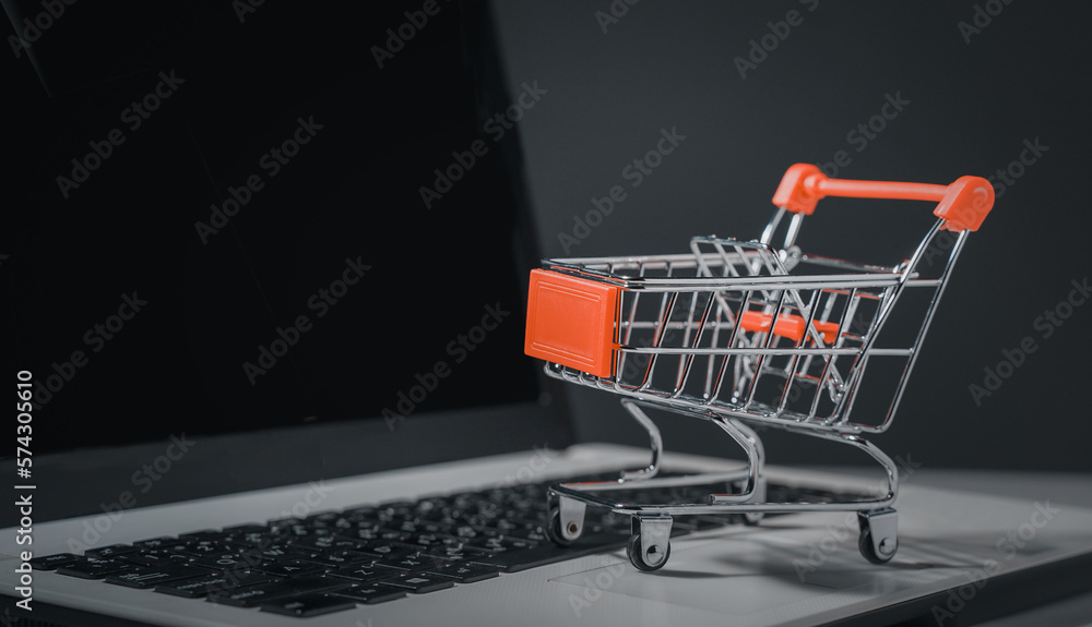 Shopping online. Trolley in front laptop keyboard. Business retail shop store marketing online. Shipping service technology, order check out website, home delivery package, client buying on e-commerce