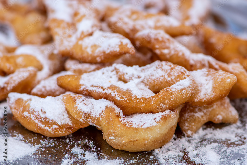 Fried pastrie of Carnival, strips of fried dough typically made on Mardi Gras covered by powdered sugar, close up Fried pastrie of Carnival, strips of fried dough typically made on Mardi Gras covered by powdered sugar, close up