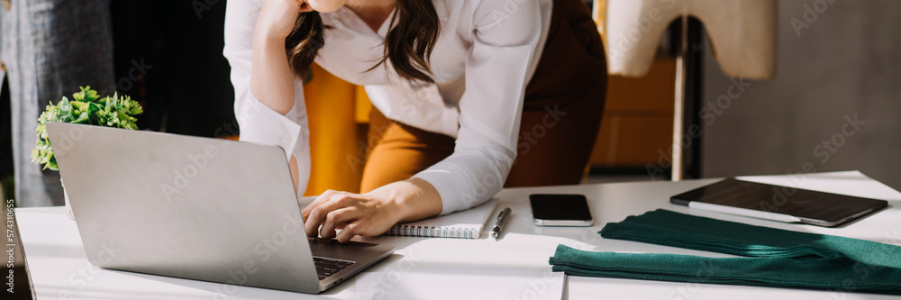 Fototapeta premium Fashion blogger concept, Young women selling clothes on video streaming.Startup small business SME, using smartphone or tablet taking receive and checking in studio