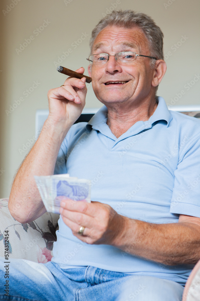 Retirement: In the money. A smug, satisfied look on the face of an affluent senior man enjoying a cigar. From a series of related images. Retirement: In the money. A smug, satisfied look on the face of an affluent senior man enjoying a cigar. From a series of related images.