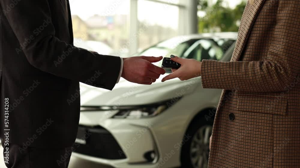 Woman taking keys from her new car in a car showroom Woman taking keys from her new car in a car showroom