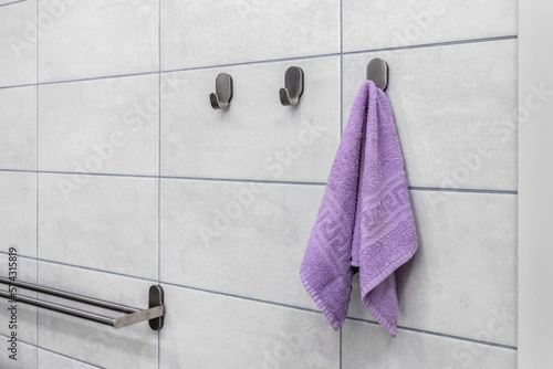 A small purple towel hangs on a metal hook