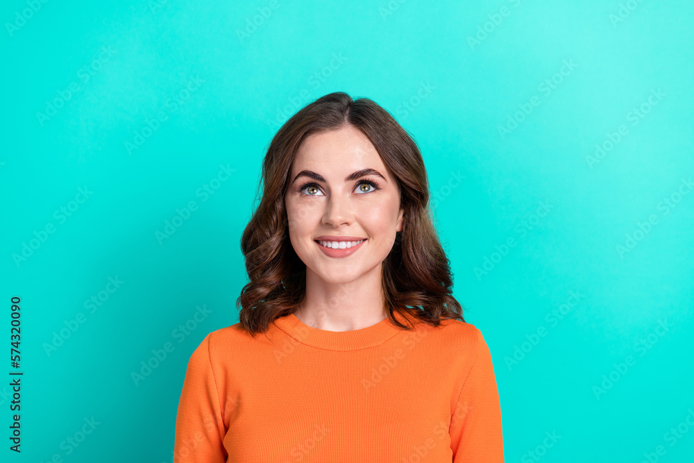 Closeup photo of young positive brown curly hairstyle smile wear orange shirt look up empty space promo new shop isolated on cyan color background Closeup photo of young positive brown curly hairstyle smile wear orange shirt look up empty space promo new shop isolated on cyan color background