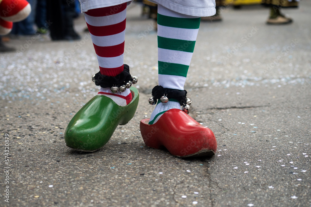 Closeup of feet of man wearing red and green socks and  wooden shoes in the street during the carnival